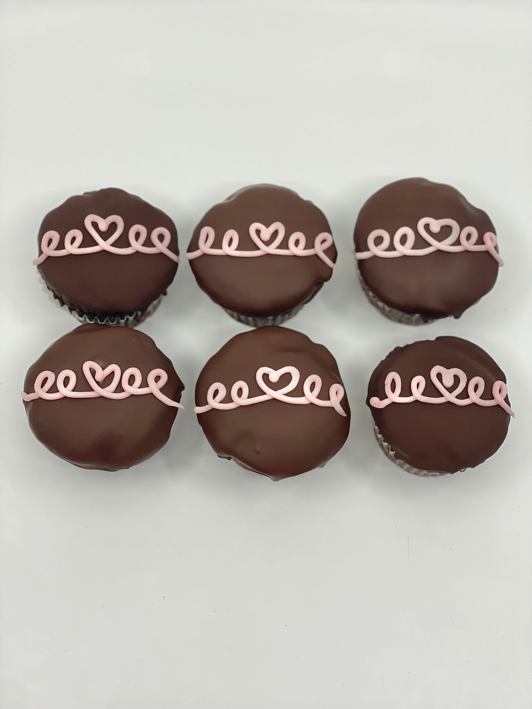 chocolate cupcakes frosted with chocolate frosting and pink heart swirls