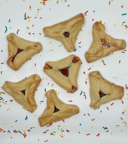 Hamantaschen cookies, chocolate or strawberry filled.  Sprinkles are present on the otherwise white background.